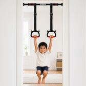 A young boy is shown using a wall-mounted pull-up bar with hanging rings in a bright, modern room. The pull-up bar is branded with the word 'SLOVIC' at the top center.