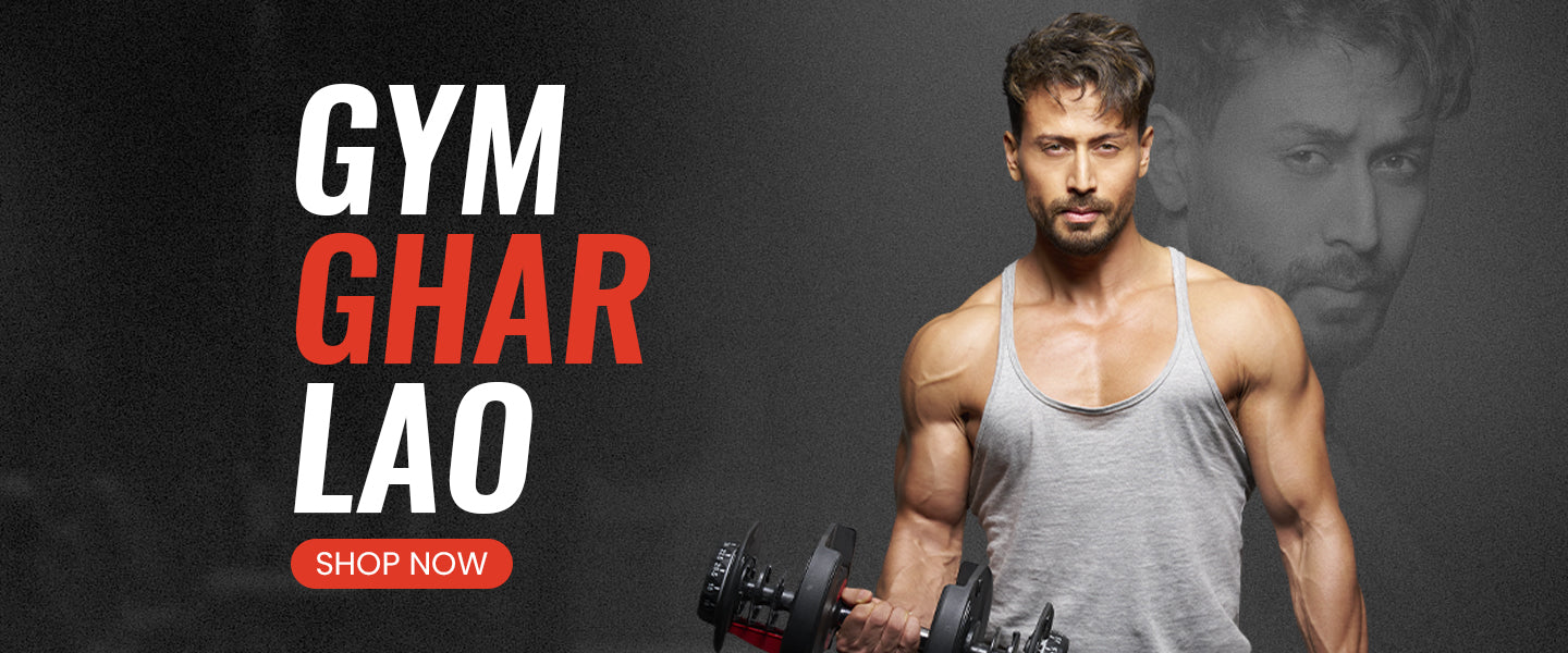 Tiger Shroff holding Slovic dumbbells with promotional text 'GYM GHAR LAO SHOP NOW' on a dark background